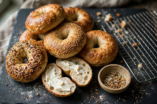 Homemade chewy sourdough bagels with everything and sesame seasoning on a dark slate slab