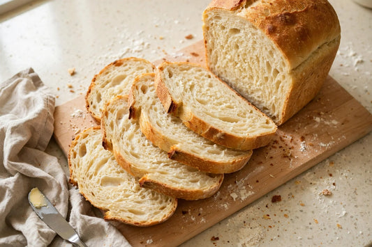 Soft golden sourdough discard milk bread loaf, sliced, on a maple board