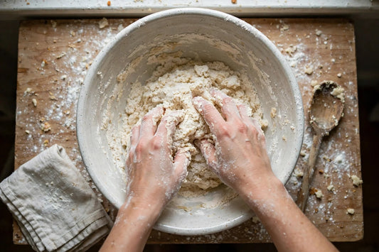 Hands mixing dough in a ceramic bowl